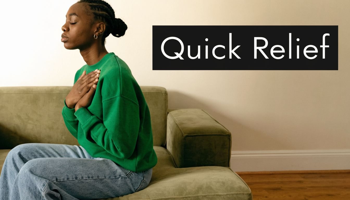 A young woman sits on a couch with eyes closed, hands on her chest, seeking calm and relief.