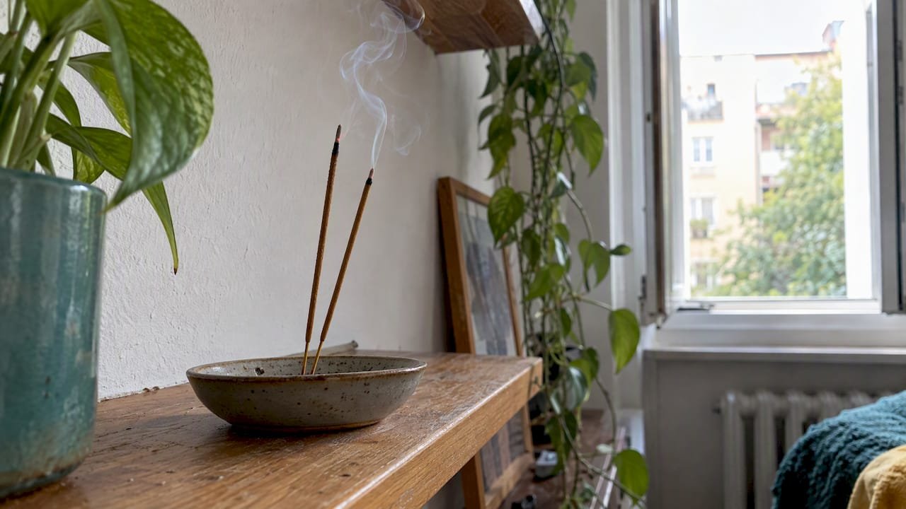 Incense sticks burning beside an open window